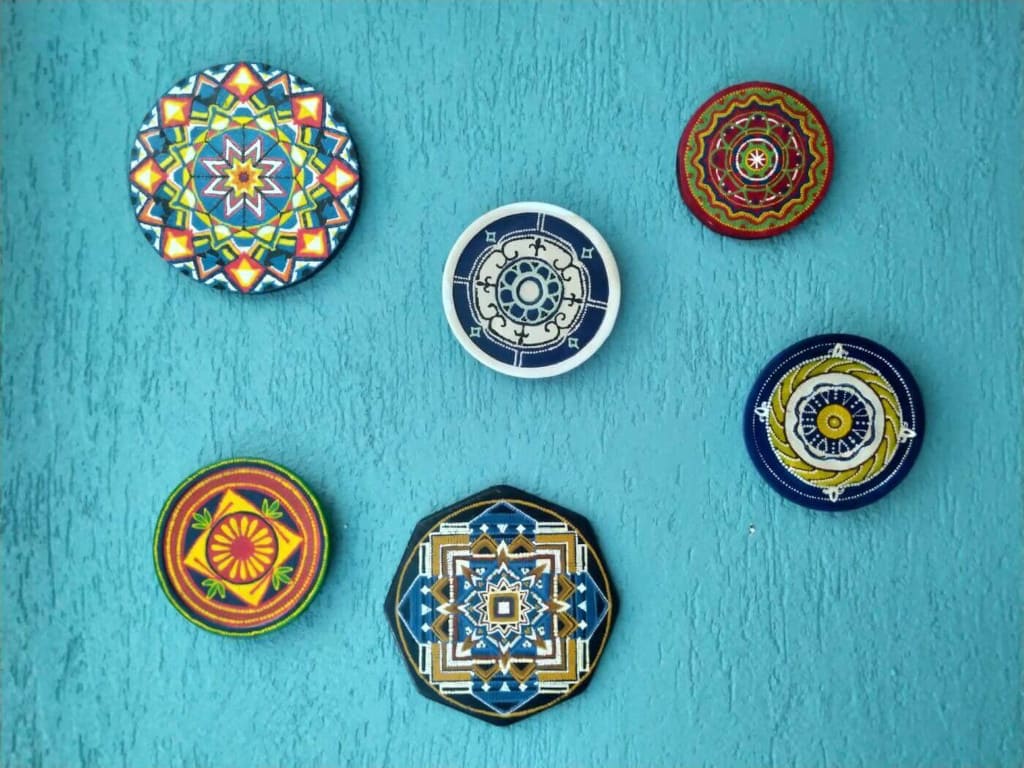 Mandale namalowane na płytach drewnianych. U góry od lewej: grenlandzka, hiszpańska, lapońska. U dołu od lewej: romska, aztecka, meksykańska.