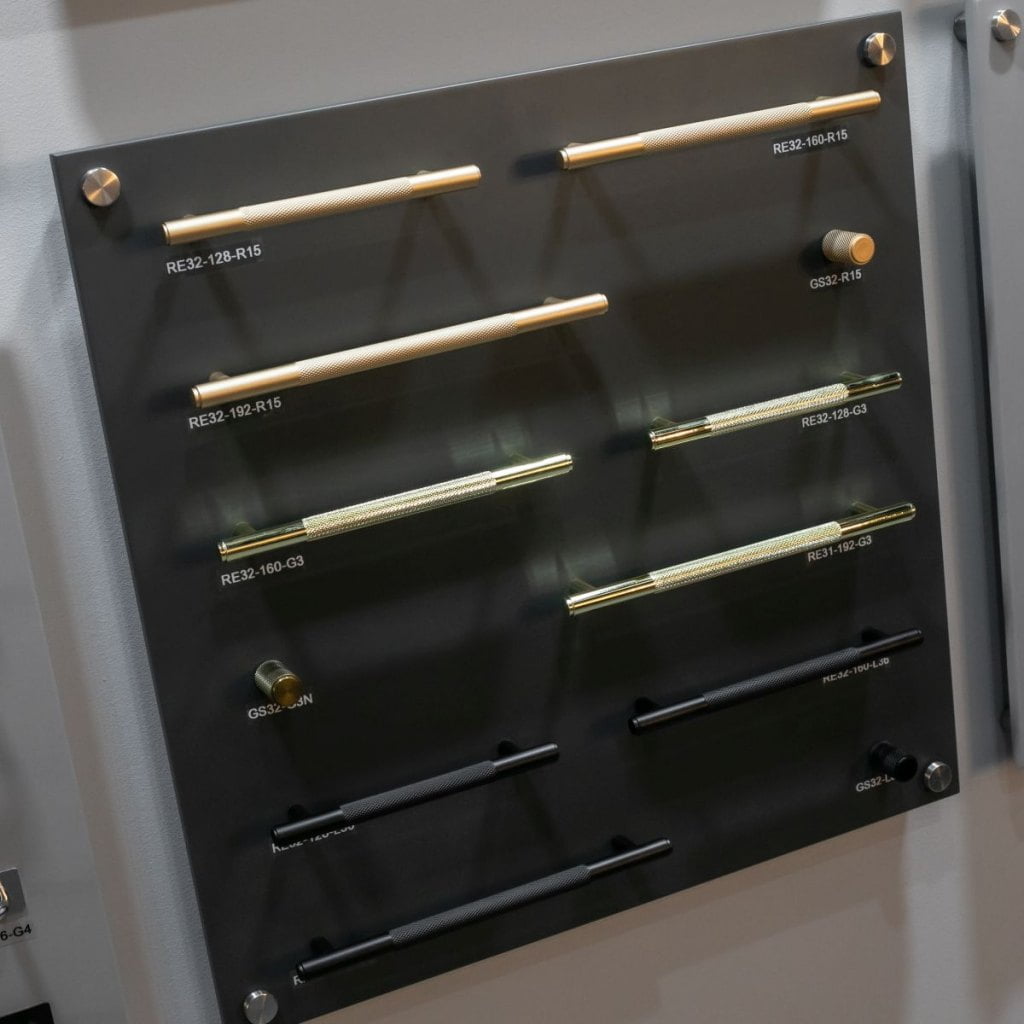 Złote i czarne uchwyty meblowe firmy Gamet prezentowane na czarnej  ściance podczas tragów  Warsaw Home & Contract 2021 - miesięcznik i portal informacyjny branży meblarskiej biznes.meble.pl