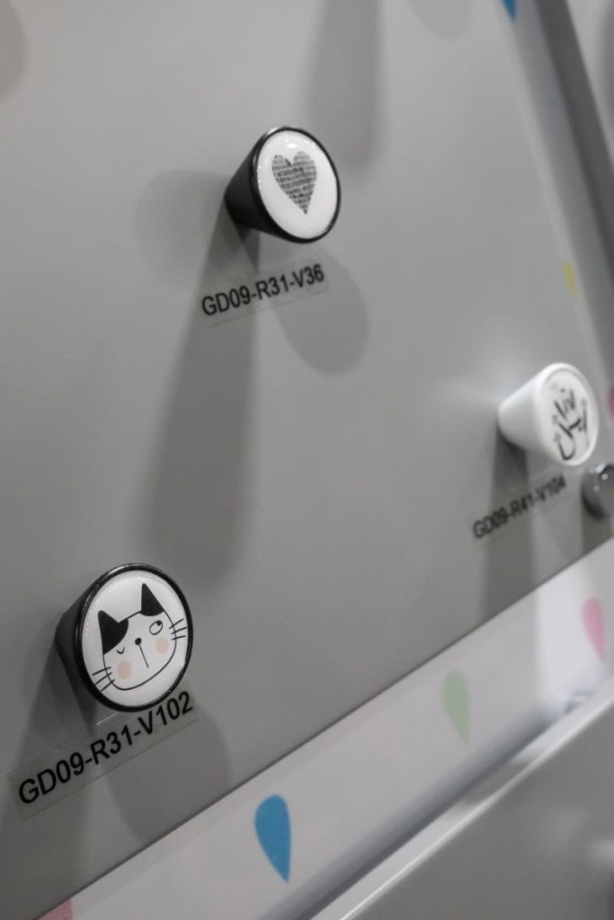 Dziecięce gałki meblowe firmy Gamet w kolorze biało-czarnym z motywem serca i kota prezentowane na szarej ściance podczas tragów  Warsaw Home & Contract 2021 - miesięcznik i portal informacyjny branży meblarskiej biznes.meble.pl