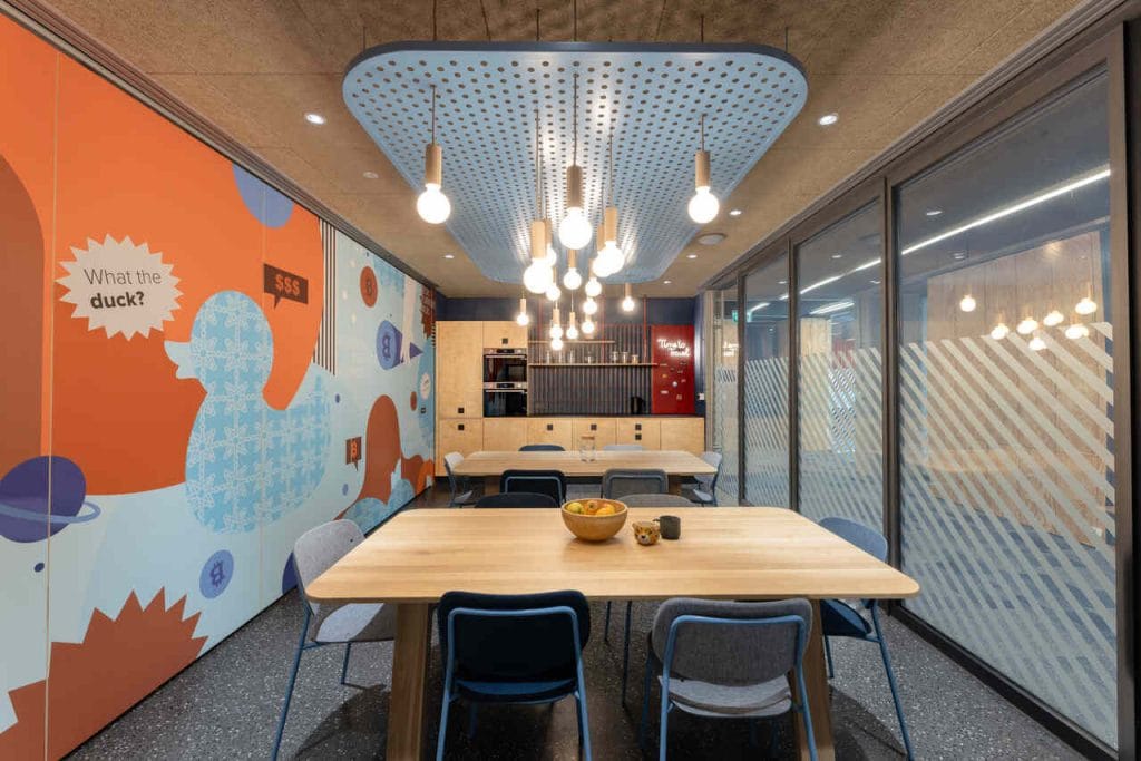 Projektując tę przestrzeń, udało nam się zachować 80% układu funkcjonalnego, co pozwoliło znacząco obniżyć koszty. Dużym wyzwaniem był ciemny korytarz, który po remoncie zyskał nowe życie dzięki caffé pointom oraz zielonej ścianie. Aby nadać mu więcej wyrazu wprowadziliśmy energetyczny wzór na wykładzinie. Unikalny charakter biura tworzą wielkoformatowe ilustracje autorstwa Poli Augustynowicz, przedstawiające ‘inside jokes’ z branży IT” – mówi architektka Karolina Kowalik z pracowni AKA Studio o biurze firmy z branży FinTech. Fot. W_Środku.