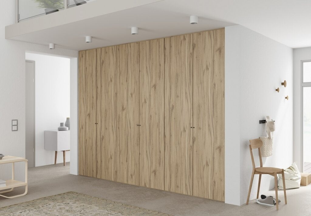 Dekor Justus firmy Interprint w kolorze jasnego drewna pokazany na szafie w białym we wnętrzu - miesięcznik i portal informacyjny branży meblarskiej biznes.meble.pl