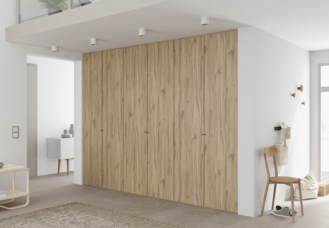 Dekor Justus firmy Interprint w kolorze jasnego drewna pokazany na szafie w białym we wnętrzu - miesięcznik i portal informacyjny branży meblarskiej biznes.meble.pl