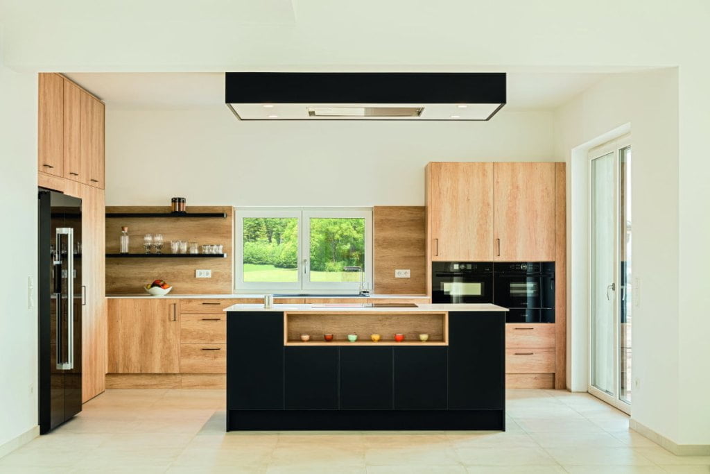 Jasna kuchnia z motywem drewna oraz czerni z blatami roboczymi Egger