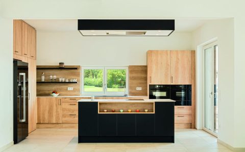 Jasna kuchnia z motywem drewna oraz czerni z blatami roboczymi Egger