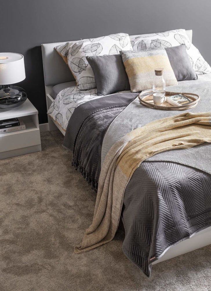 Łóżko, sypialnia w ciepłej, pastelowej kolorystyce.