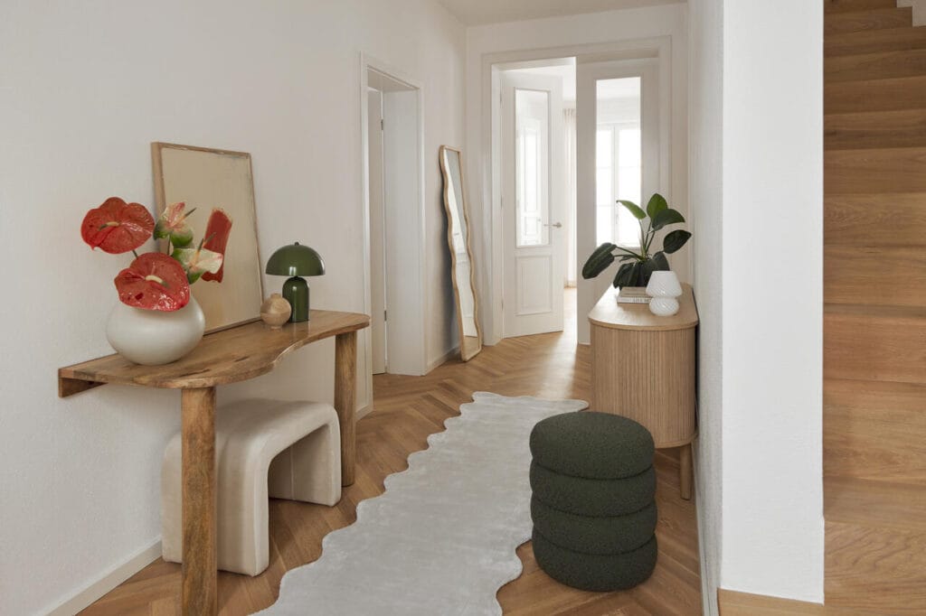 Korytarz – bardzo często wąskie pomieszczenie z nienajlepszą ekspozycją światła, sprawia, że nie wiemy, jak praktycznie go urządzić. Ławki i pufy umożliwią wygodne założenie butów. Lustro powieszone na ścianie optycznie powiększy pomieszczenie, a lampy dodadzą mu klimatycznego nastroju. Fot. Westwing.