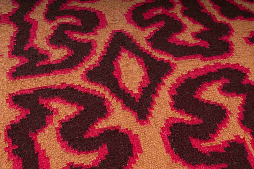 Tekstylia na styku rzemiosła i cyfrowości: rysunki są przenoszone do cyfrowych renderingów, a następnie implementowane jako żakardy lub hafty. W rezultacie powstają prace wizualizujące dialog między mediami analogowymi i cyfrowymi. Charakterystycznymi cechami są motywy przypominające zakłócenia, pikselowe gradienty kolorów oraz cyfrowo modyfikowane rysunki odręczne. Na zdjęciu dywan Ember, proj. Stefania Ruggiero, technika kilimowa, Delvis (Un)limited, 2024. Fot. Piercarlo Quecchia. Źródło: Heimtextil.