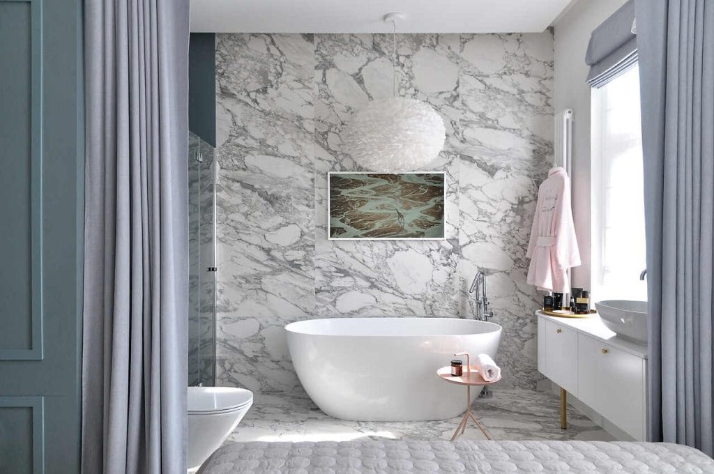 Oligami – sypialnia z łazienką w apartamencie w gdańskiej kamienicy. Teatralność strefy łazienki widziana z łóżka. Wanna w roli głównej. Zasłony sterowane elektrycznie dają możliwość szybkiego oddzielenia stref i uzyskania łazienkowej intymności.