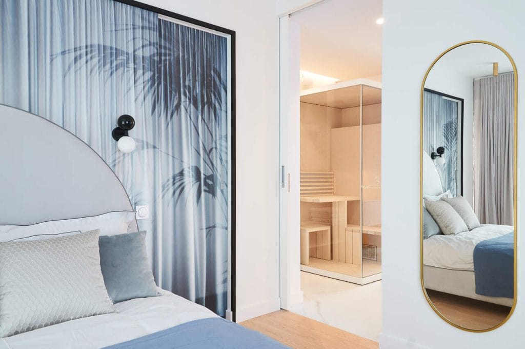 Rhino in Wonderland – sypialnia główna w domu w Gdyni. Połączona z łazienką wyposażoną w saunę. Tuż za łóżkiem ukryta została garderoba. Przesuwne drzwi ozdobione tapetą ukrywają subtelnie tę strefę.