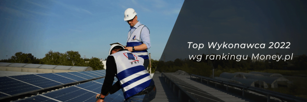 Dwóch panów w białych kaskach i kamizelkach montuje panele fotowoltaiczne na dachu budyknu - miesięcznik i portal informacyjny branży meblarskiej biznes.meble.pl