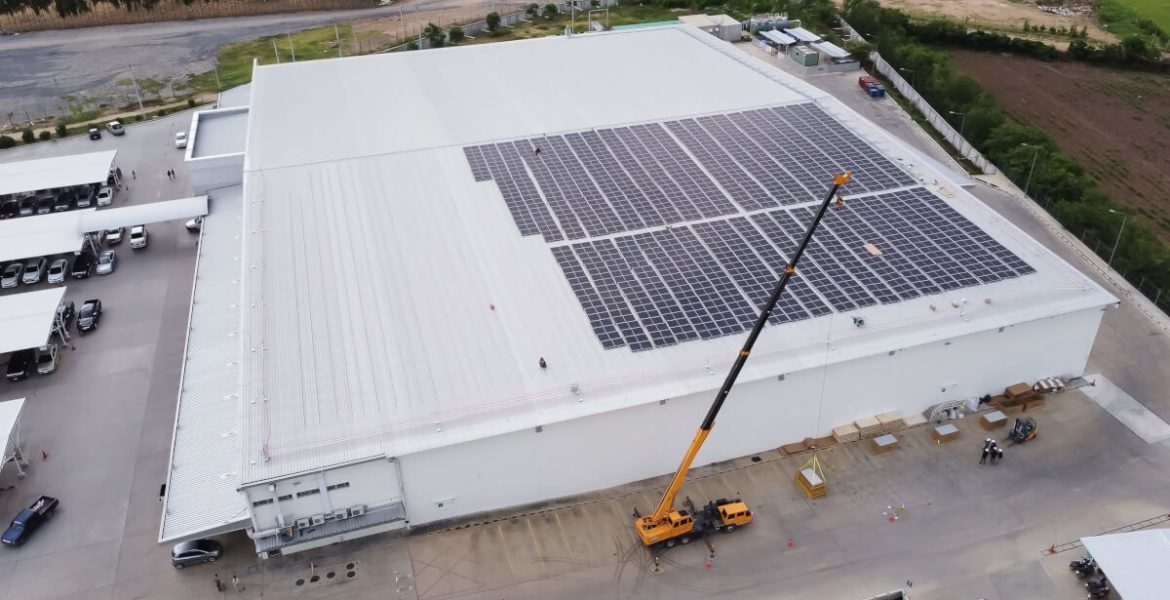 Proces zakładania przez dźwig paneli fotowoltaicznych na dużym białym dachu magazunu realizowane przez PKF - miesięcznik i portal informacyjny branży meblarskiej biznes.meble.pl