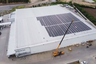 Proces zakładania przez dźwig paneli fotowoltaicznych na dużym białym dachu magazunu realizowane przez PKF - miesięcznik i portal informacyjny branży meblarskiej biznes.meble.pl