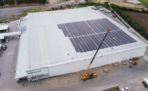 Proces zakładania przez dźwig paneli fotowoltaicznych na dużym białym dachu magazunu realizowane przez PKF - miesięcznik i portal informacyjny branży meblarskiej biznes.meble.pl