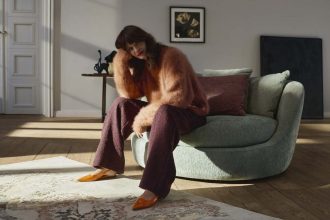 Fotel Ø od BoConcept to mebel zaprojektowany przez Helenę Christensen, inspirowany duńskimi wyspami i ideą domowej oazy spokoju. Jego zakrzywiona, oversize’owa sylwetka otula ciało miękkimi poduszkami, tworząc przestrzeń idealną do relaksu. Ø to nie tylko fotel – to rzeźbiarska forma, która przyciąga wzrok i zapewnia komfort. Wersja tapicerowana szałwiową tkaniną Lucca dodaje wnętrzu subtelnej elegancji i naturalnego ciepła. Dzięki starannie dobranym materiałom i przemyślanej konstrukcji, Ø staje się osobistą wyspą wypoczynku – miejscem, w którym można się zanurzyć i odpocząć. Fot. Wetouch Imagework.