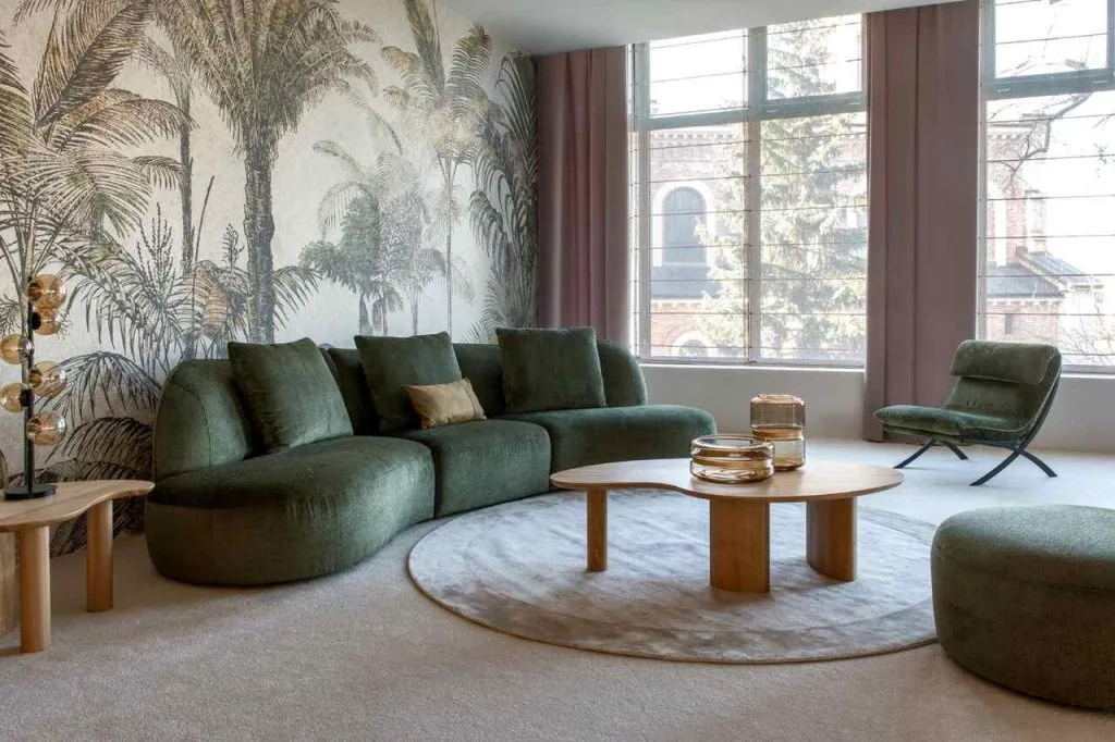Narożnik Sirena marki KLER, której salon znajduje się na terenie Galerii Wnętrz DOMAR, przyciąga uwagę ponadczasową formą oraz tkaniną z kolekcji Accadia w szlachetnym, zielonym odcieniu. Dzięki modułowej konstrukcji z trzech brył (bez klasycznych podłokietników) zapewnia więcej miejsca do siedzenia i daje możliwość tworzenia różnych układów. Wysokiej jakości pianki, włókniny i sprężyny w siedziskach oraz oparciach gwarantują komfort i trwałość. Narożnik ma 345 cm szerokości, 146 cm głębokości i 93 cm wysokości, przez co doskonale sprawdzi się w przestronnym salonie lub eleganckim gabinecie. W zestawie dostępny jest również dopasowany puf.