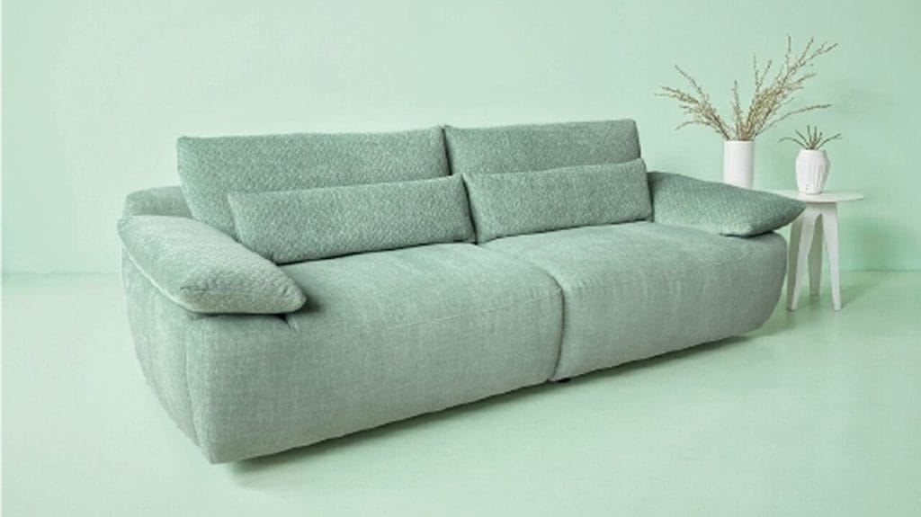 Sola to nowy produkt ROM w kolekcji Nuance. Mebel wprowadza do kolekcji nowy język projektowania: płynne krągłości w połączeniu z maksymalnym komfortem dzięki obszernemu siedzisku blokowemu. Elegancko umieszczone na górze, zwężające się poduszki na ramiona i oparcia, dają poczucie lekkości i wyrafinowania. To, co sprawia, że Sola jest naprawdę wyjątkowa, to połączenie prawie niewidocznego zmotoryzowanego podnóżka z regulowaną funkcją oparcia. Razem tworzą przestronną, odchylaną powierzchnię dla maksymalnego relaksu. Kolejną atrakcją jest to, że pod podnoszoną poduszką podłokietnika ukryty jest akumulator, który zasila funkcje elektryczne. Zdjęcia przedstawiają idealnie skoordynowane połączenie tkanin 3D Bubble z Escana. Projekt: Paul Falkenberg.