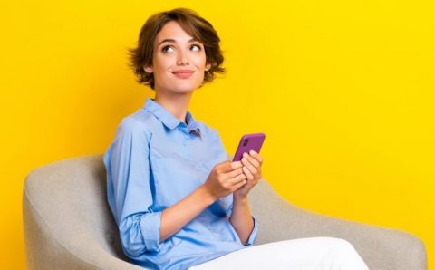 Unity Group, pani z komórką w ręce siedząca na krześle -miesięcznik i portal informacyjny branży meblarskiej biznes.meble.pl