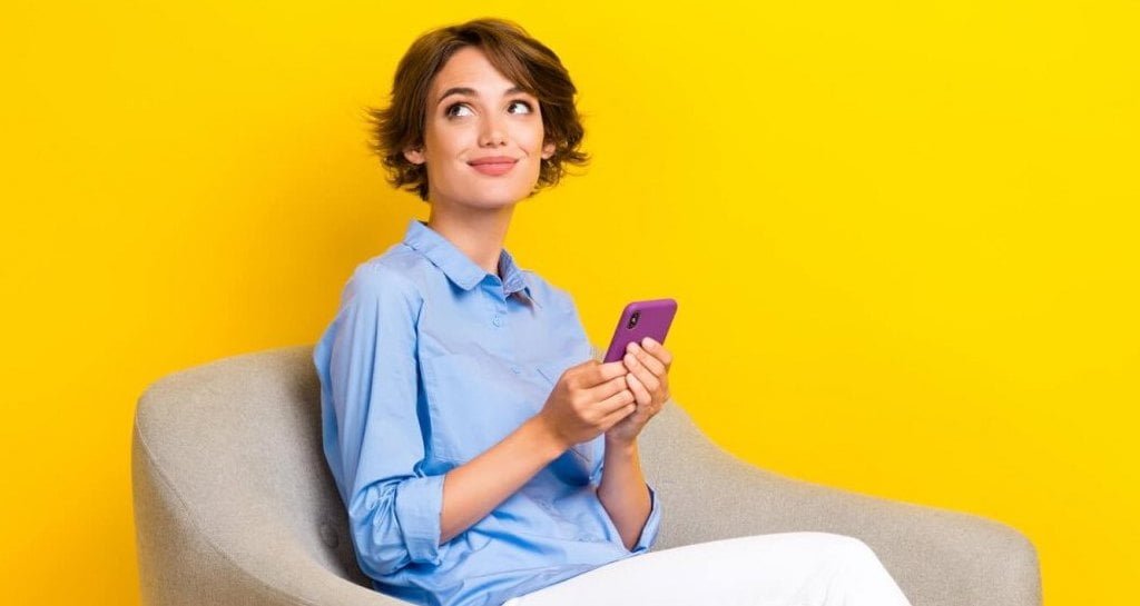 Unity Group, pani z komórką w ręce siedząca na krześle -miesięcznik i portal informacyjny branży meblarskiej biznes.meble.pl