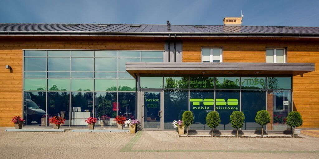 Charakterystyczna drewniana elewacja i zielone logo na fasadzie firmowego salonu Tobo w Kurianach koło Białegostoku.