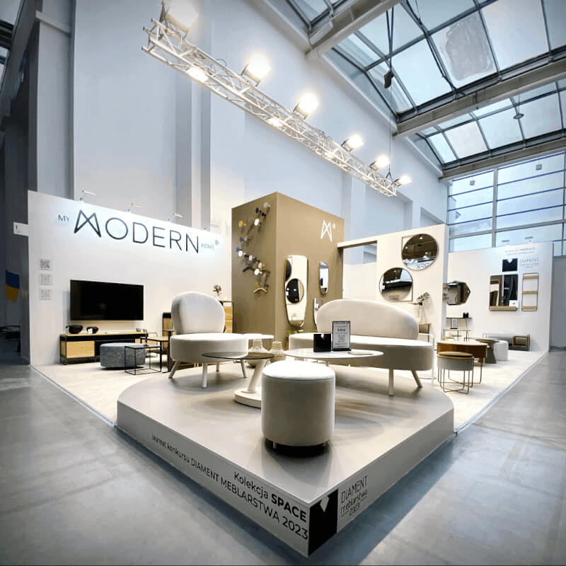 Stoisko My Modern Home na targach Meble Polska 2023, wieszaki na ubrania w różnych kolorach zawieszone na brązowej ścianie - miesięcznik i portal informacyjny branży meblarskiej biznes.meble.pl