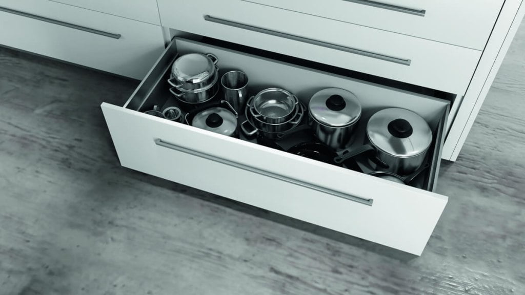 Otwarta szuflada z garnkami na prowadnicach F70 firmy Salice w białej kuchni z brązowym blatem - miesięcznik i portal informacyjny branży meblarskiej biznes.meble.pl