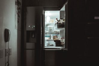 Oświetlone wnętrze lodówki w ciemnym pomieszczeniu.