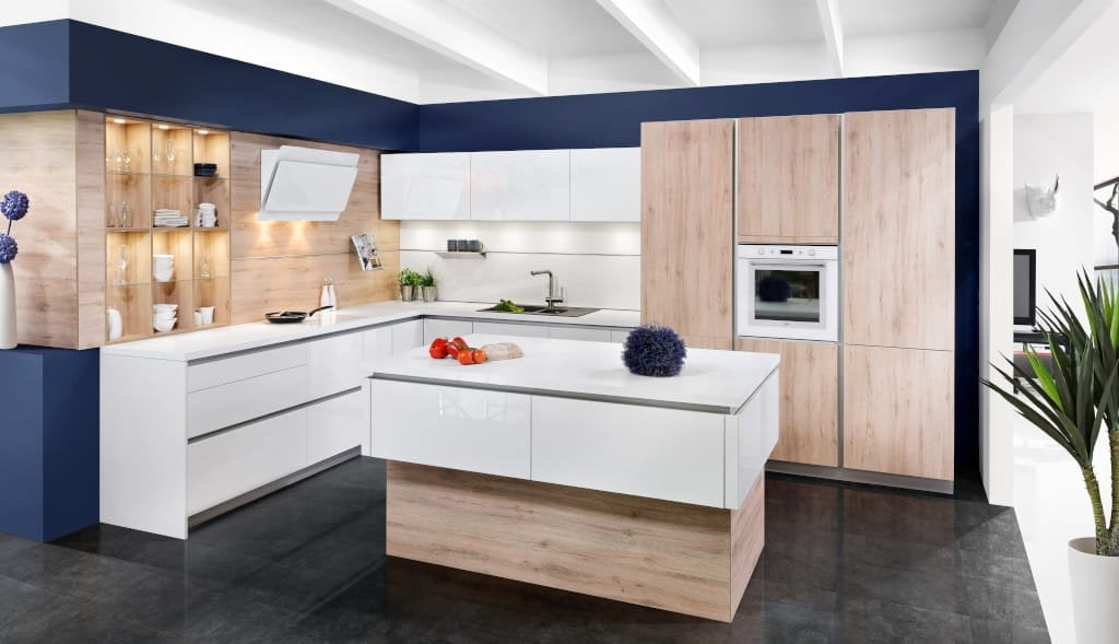 W kolekcji „KAMmoduł Proline” firmy KAM biały połysk zestawiono z dekorem „Dąb Saint Tropez”. Wyspa w tej kuchni wyróżnia się oryginalnym kształtem – nakładanymi bokami kątowymi.