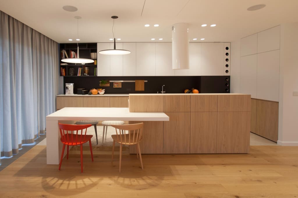 Kuchnia z naturalnym fornirem dębowym (proj. Kaeel Group, realizacja – Studio Prostych Form). Całość jest zintegrowana stylistycznie z zabudową salonu.