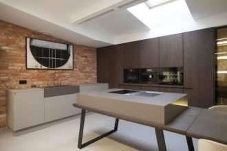 Szare meble kuchenne pokryte multifunkcjonalną zaprawą kwarcową „Ecomalta” to jedna z realizacji Studia Prostych Form. Na stole: płyta ze zintegrowanym w blacie pochłaniaczem firmy Bora.