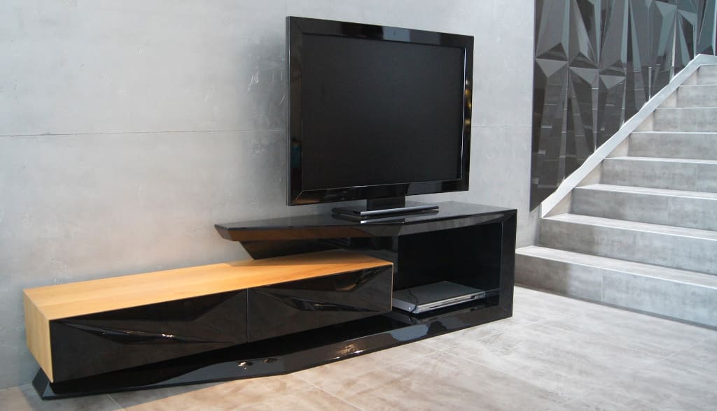 Prezentowana szafka RTV to propozycja firmy Naturano. Wykonano ją w lakierze na wysoki połysk z wykorzystaniem frontów „Del”. Korpusy szuflad są fornirowane.