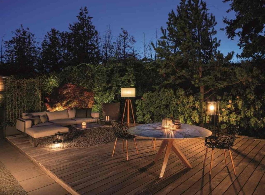 Sofa wypoczynkowa, stół jadalny z naturalnego kamienia, nastrojowe oświetlenie i dywan na zewnątrz tworzą przytulną atmosferę w salonie na świeżym powietrzu. Fot. VDM/Draenert.