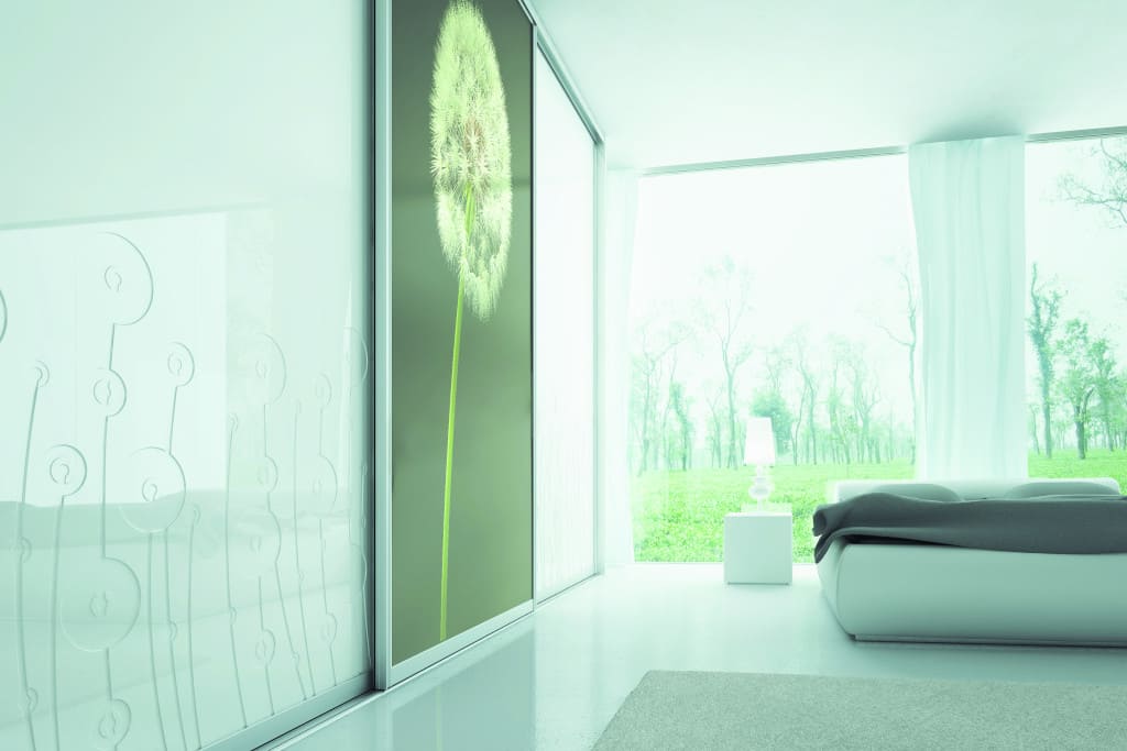 W prezentowanej sypialni wykorzystana został druk cyfrowy z wzorem dmuchawca. W szafie zastosowano system oparty na profilu aluminiowym „Onyx” firmy Komandor.