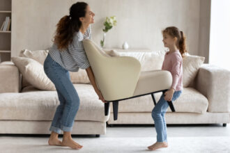 Pani z dziewczynką przenosi biały fotel - Badania Inquiry - miesięcznik i portal informacyjny branży meblarskiej