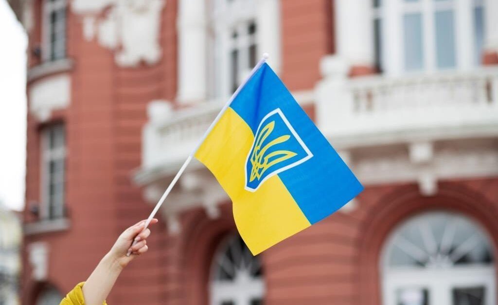 Ukraińska flaga na tle budynku to symbol zaangażowania w projekt Odbudowa Ukrainy.