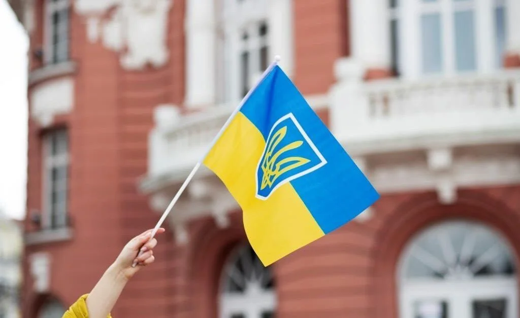 Ukraińska flaga na tle budynku to symbol zaangażowania w projekt Odbudowa Ukrainy.