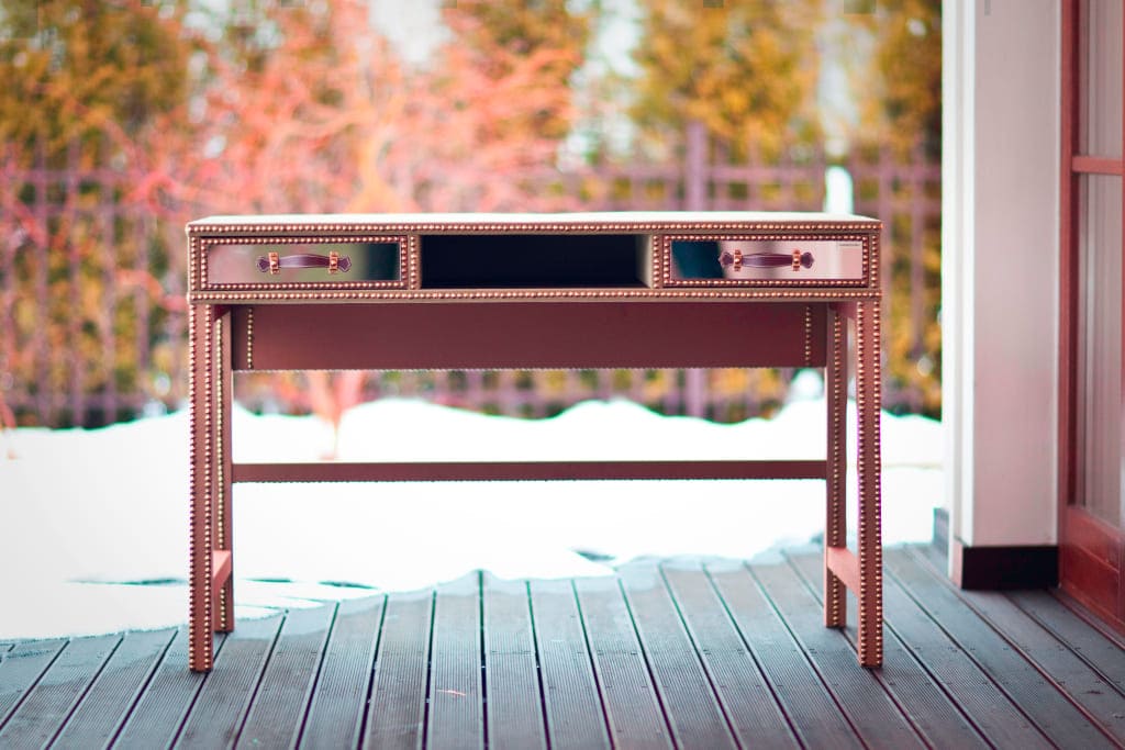 Biurko „Ex Libris” marki Ammadora zostało ubrane w tkaninę o oliwkowym odcieniu i wyposażone w mosiężno-skórzane uchwyty.