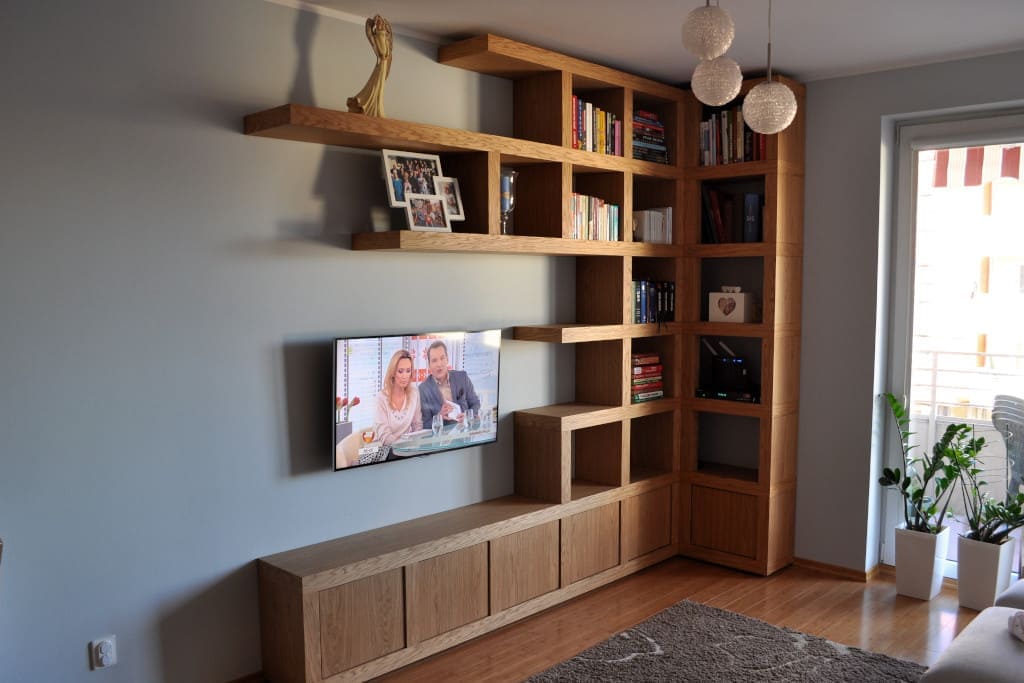 Uniwersalne regały na jedną lub dwie ściany do salonu, zaaranżowane jako biblioteczka + ścianka TV, z zamkniętymi dolnymi celami to propozycja firmy Cellaio.