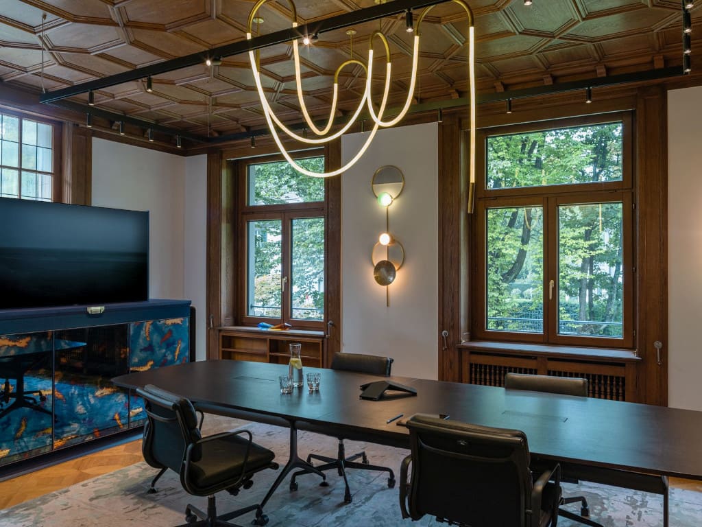 Reprezentacyjna sala konferencyjna z drewnianym stropem i świetlistymi wężami projektu studia Tank z Amsterdamu.