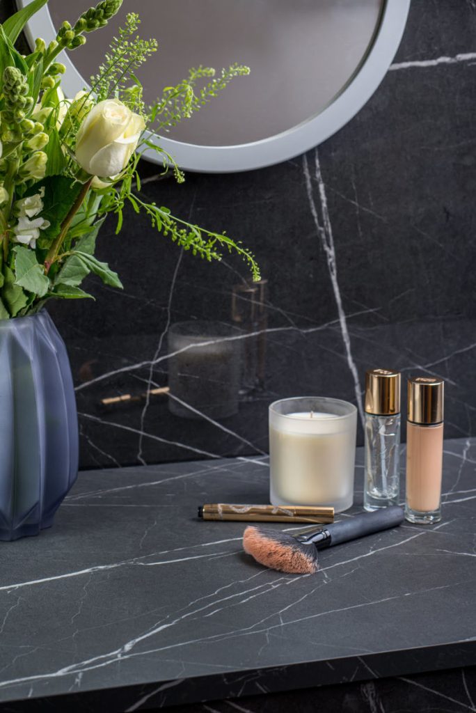 Kosmetyki i świeca na szarym, marmurowym blacie roboczym z oferty Egger 