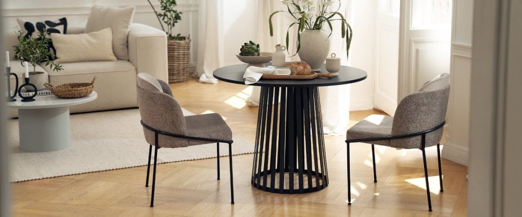Krzesła dwukolorowe z oferty Mononi przy stoliku kawowym o ażurowej podstawie.