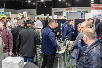 Tłum odwiedzających przy stanowisku z elektronarzędziami na targach branży drzewnej