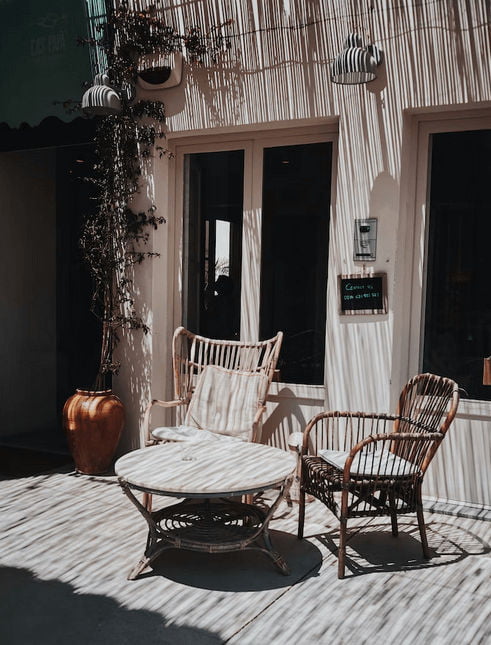 Zestaw mebli rattanowych - dwa fotele i stolik - na tarasie.