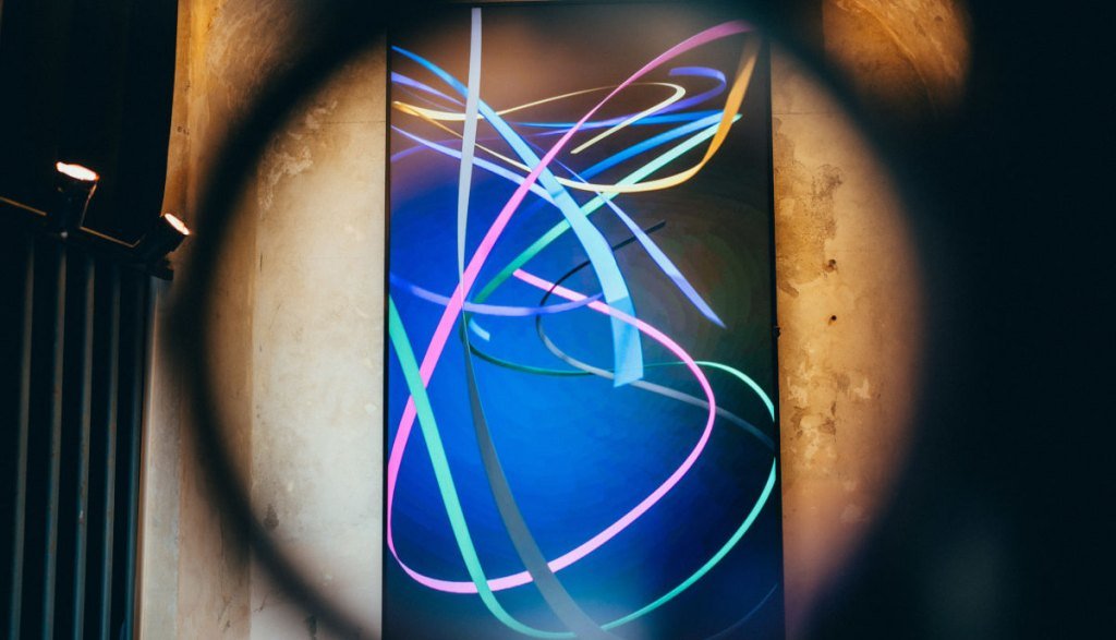 Plakat z kolorowymi wstęgami reprezentującymi linie życia na ekspozycji Impress Decor w ramach koncepcji „Imagine ... your World” podczas tygodnia designu w Mediolanie.