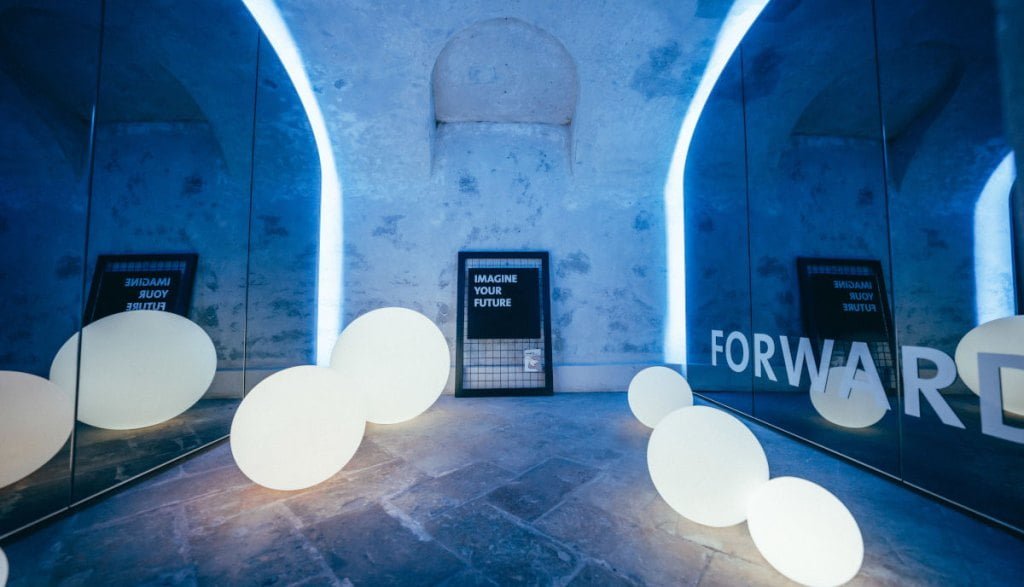 Świetlne kule w niebieskim otoczeniu na ekspozycji Impress Decor podczas tygodnia designu w Mediolanie.