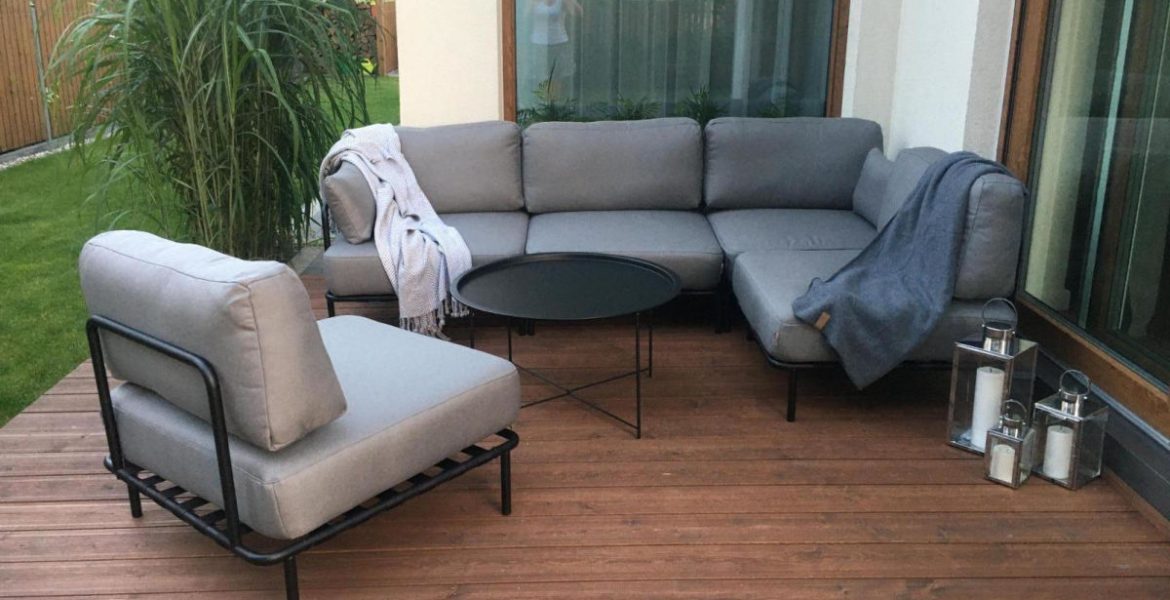 Zestaw mebli ogrodowych, sofa ogrodowa/narożnik i krzesło na drewnianym tarasie.