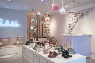 Aranżacja sklepu z obuwiem, projekt pracowni Fanajło Home Design Decor to ukłon w stronę dzieci. Na pierwszy plan wysuwają się kolorowe półkule na ścianie, które przywodzą na myśl bańki mydlane. Dopełnieniem kolorowej przestrzeni jest biel mebli potrzebnych do ekspozycji m.in. butów. Architektka Katarzyna Fanajło zadbała też o ukrycie pojemnego magazynu na buty za zasłoną. Kluczową rolę w sklepowej przestrzeni odgrywa jednak lada, która umożliwia wygodną obsługę. To miejsce, które powinno zostać dobrze doświetlone, dlatego w projekcie pojawiły się oprawy polskiej marki AQForm.