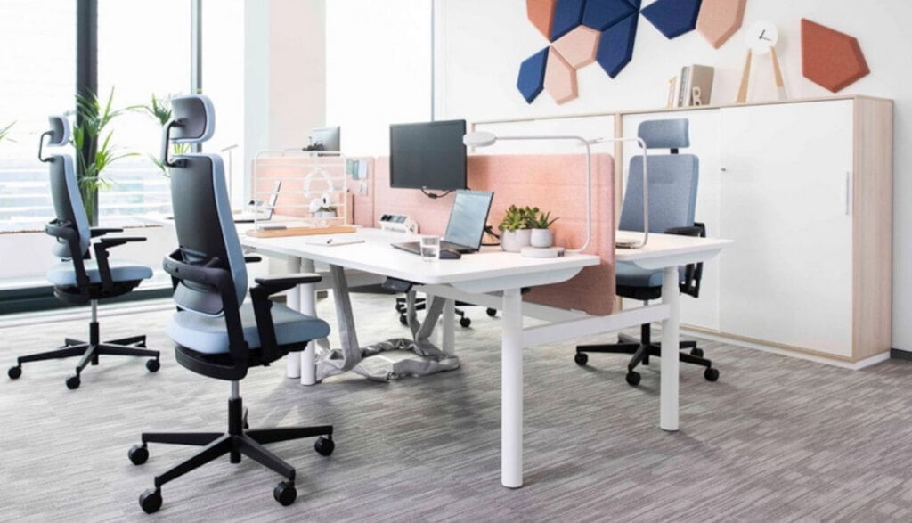 Otwarta przestrzeń biurowa open space, na pierwszym planie ergonomiczne krzesła biurowe.