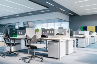 Otwarta przestrzeń biurowa open space, na pierwszym planie ergonomiczne krzesła biurowe.