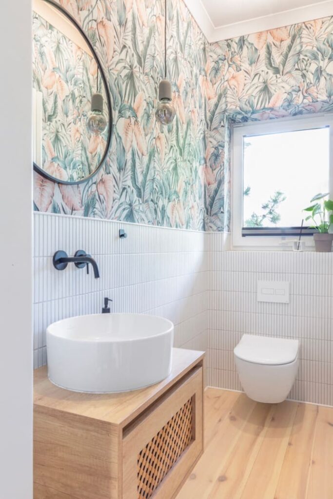 Ściany toalety zdobi tapeta w różowe kwiaty.