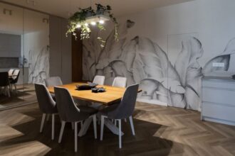 W centralnym miejscu otwartej przestrzeni kuchennej połączonej z jadalnią projektantka Agnieszka Lesiuk umieściła solidny drewniany stół, nad którym zawisła metalowa konstrukcja.